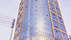 Un edificio alto y cilíndrico con fachada reflectante y estructura de entramado.