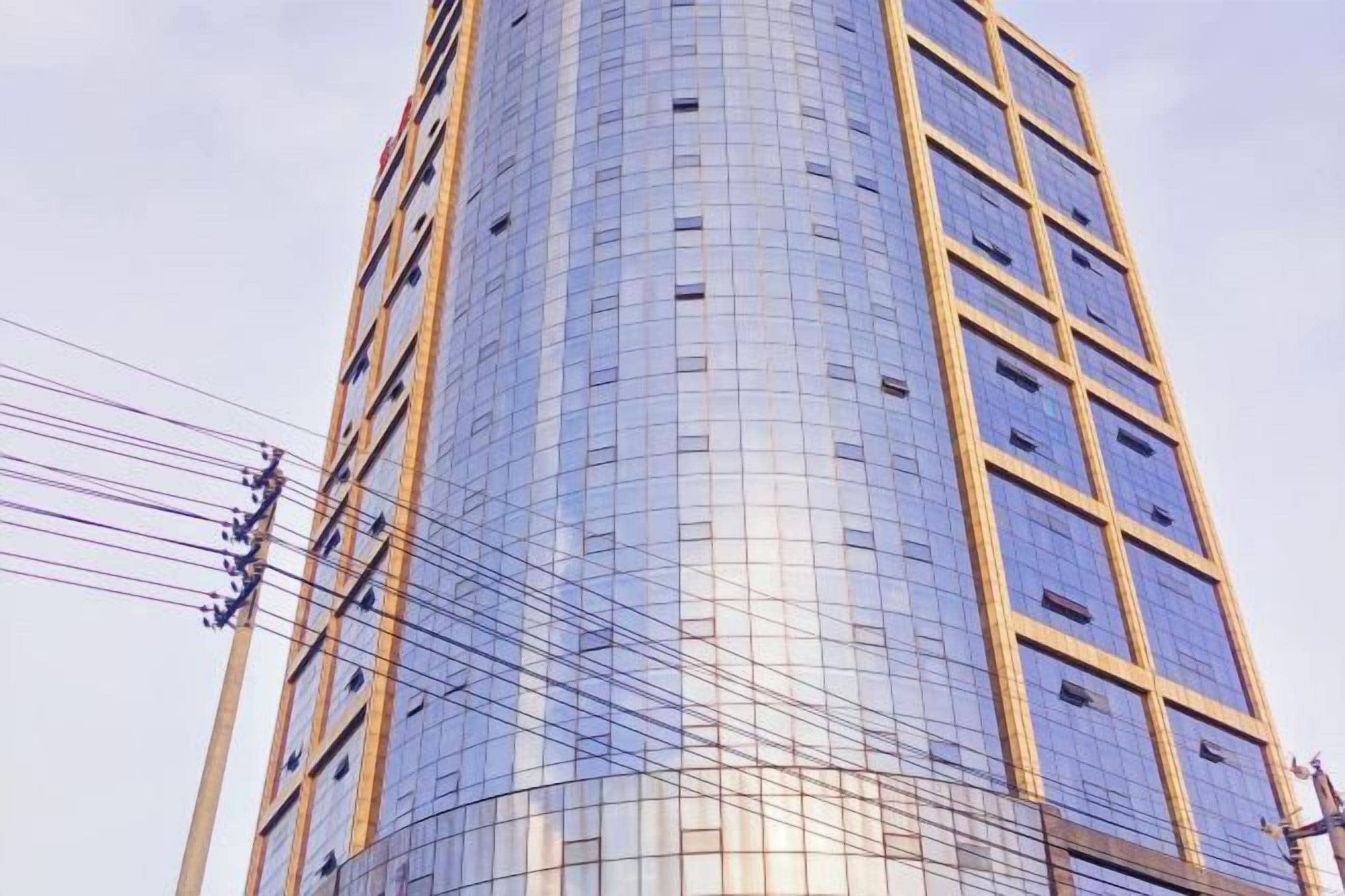 A tall, modern building with a curved facade and a grid-like pattern of windows.