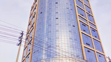 A tall, modern building with a curved facade and a grid-like pattern of windows.