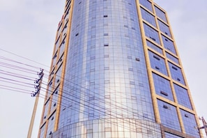 A tall, modern building with a curved facade and a grid-like pattern of windows. - Shengda Hotel (Guangshan)