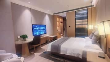 Una habitación de hotel moderna con una cama grande, un escritorio con computadora, una silla y un televisor.