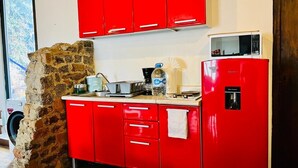 Una cocina con armarios rojos, microondas, dispensador de agua y cafetera.