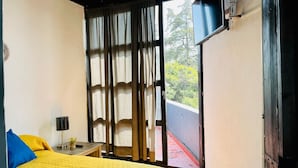 Una habitación con una cama, una mesita de noche, una lámpara y vistas a zonas verdes.