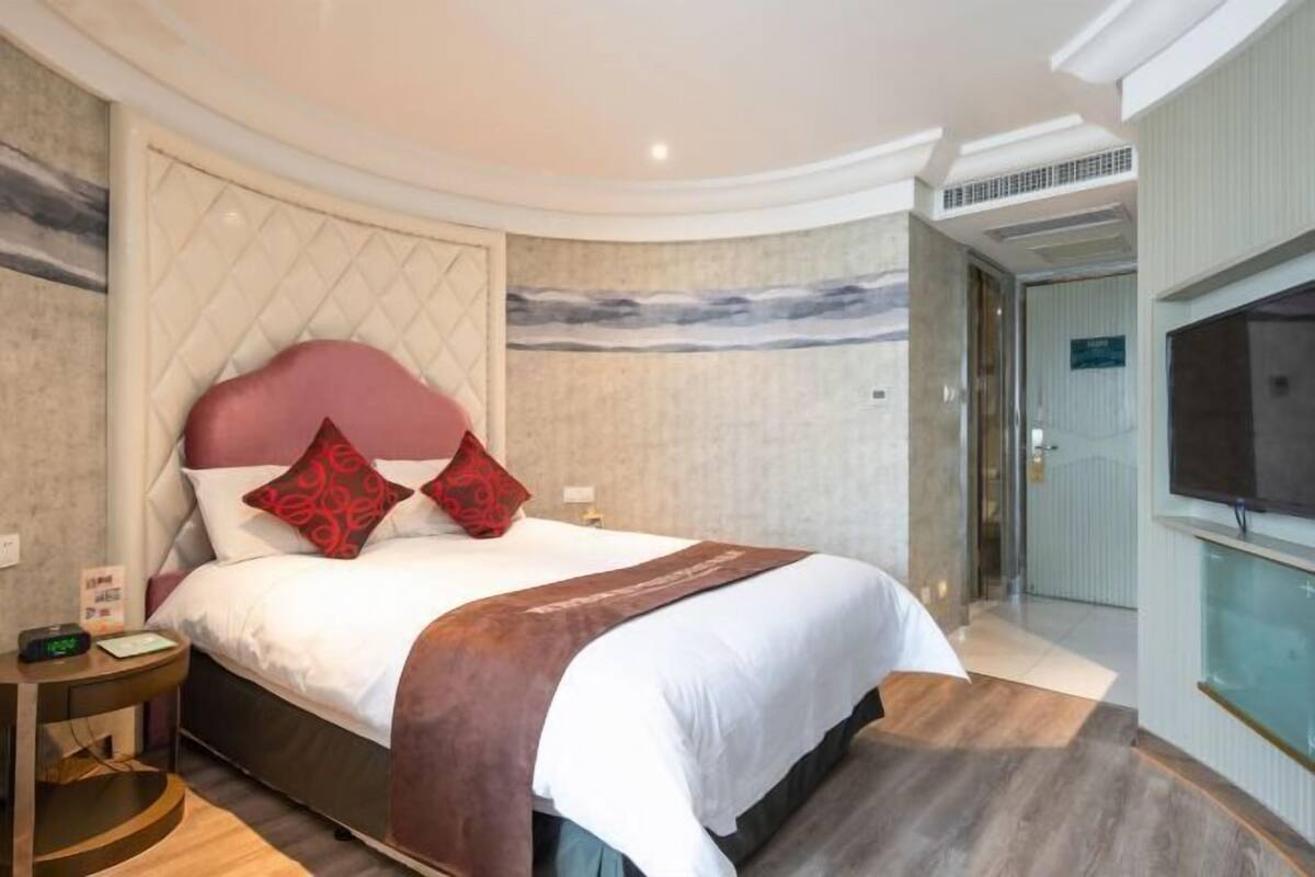 Una habitación de hotel moderna con una cama grande, un televisor y vistas a la ciudad.