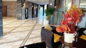 Un hall d’entrée moderne avec un sol en marbre, un comptoir d’accueil et une grande plante décorative.