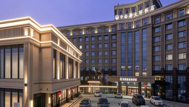 Un hôtel à plusieurs étages, doté d’une entrée imposante, de grandes fenêtres et d’une façade bien éclairée.
