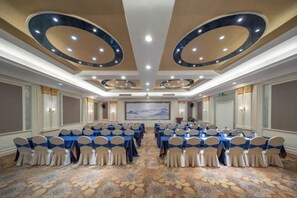 Un salón de conferencias con una mesa larga, múltiples sillas y una pantalla grande al frente.