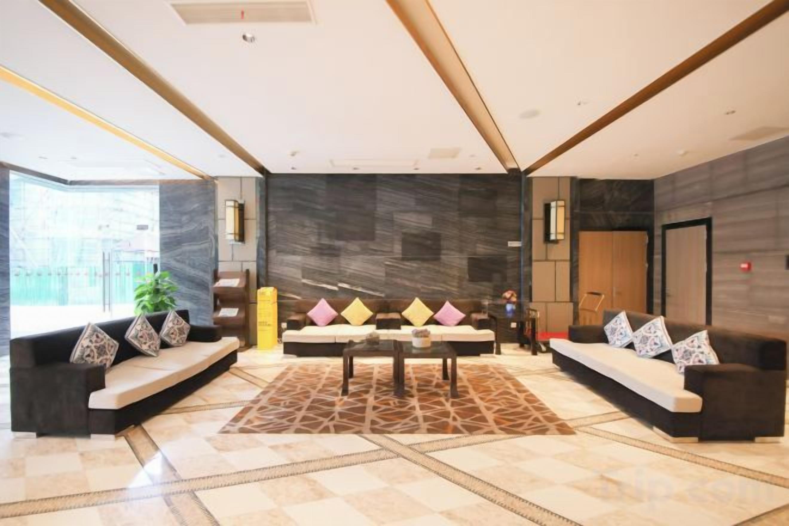 A modern lobby with a central seating area, a patterned rug, and a large window providing natural light.