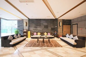 A modern lobby with a central seating area, a patterned rug, and a large window providing natural light. - Grand Daqiao Hotel (Nanjing)