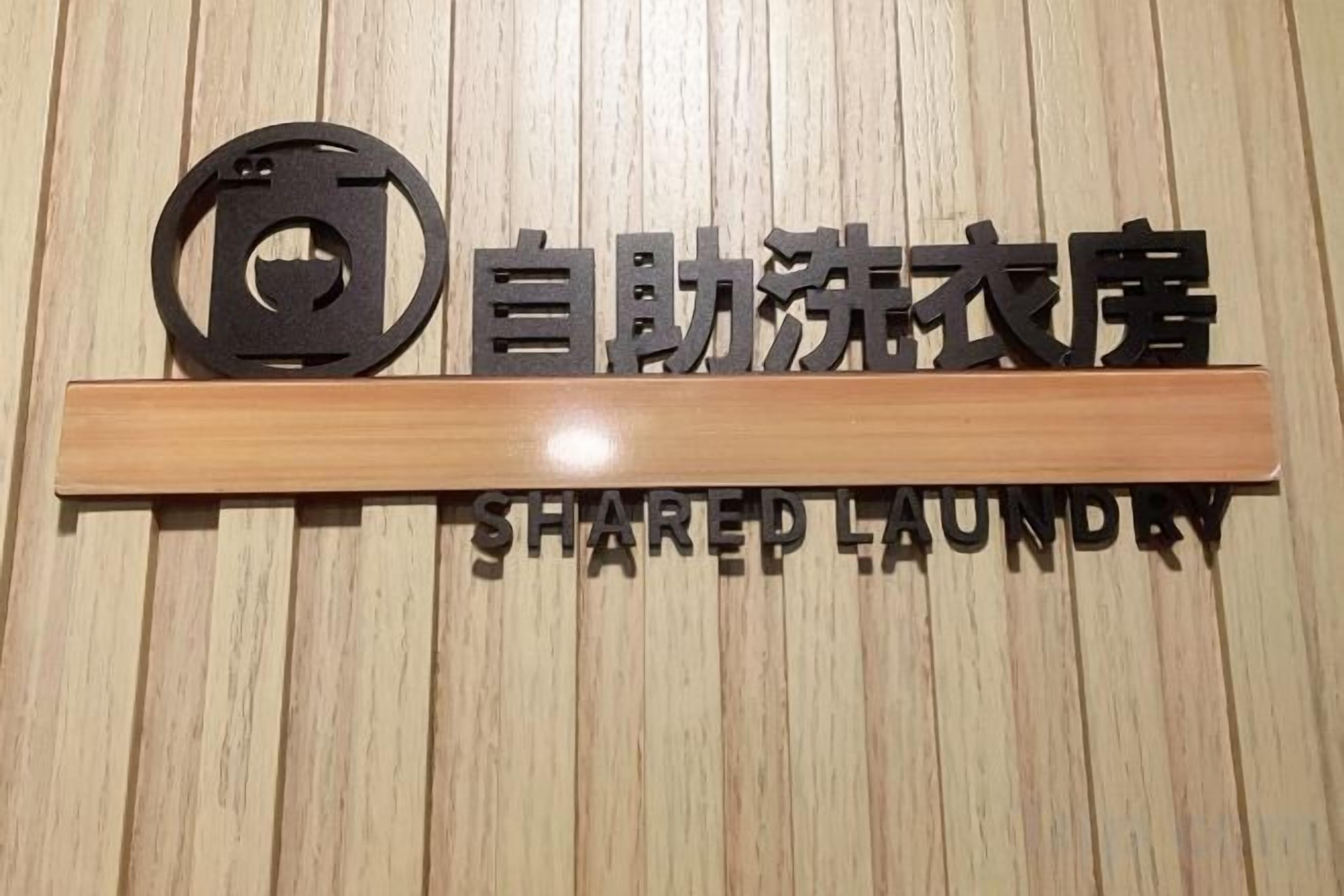 A sign with Chinese characters and the English words 'SHARED LAUNDRY' on a wooden wall.