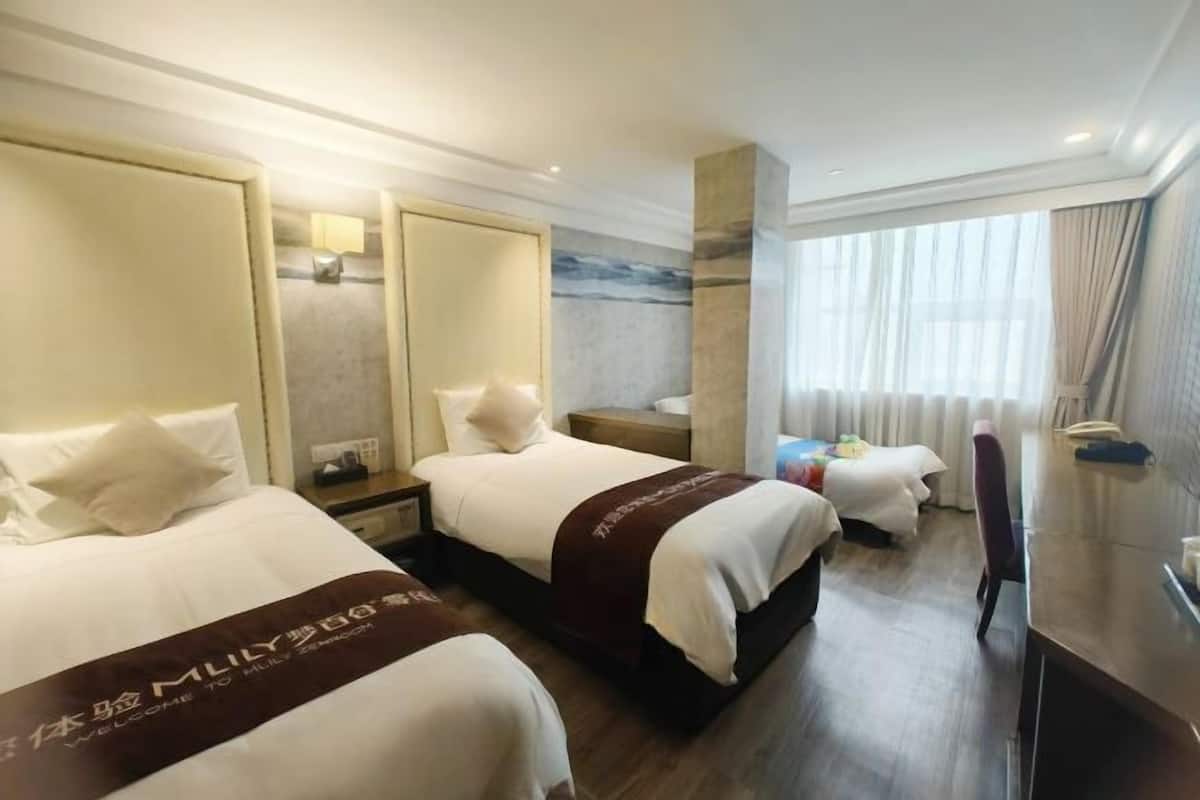 Una habitación de hotel con dos camas, un escritorio, una silla, un espejo y una ventana con cortinas.