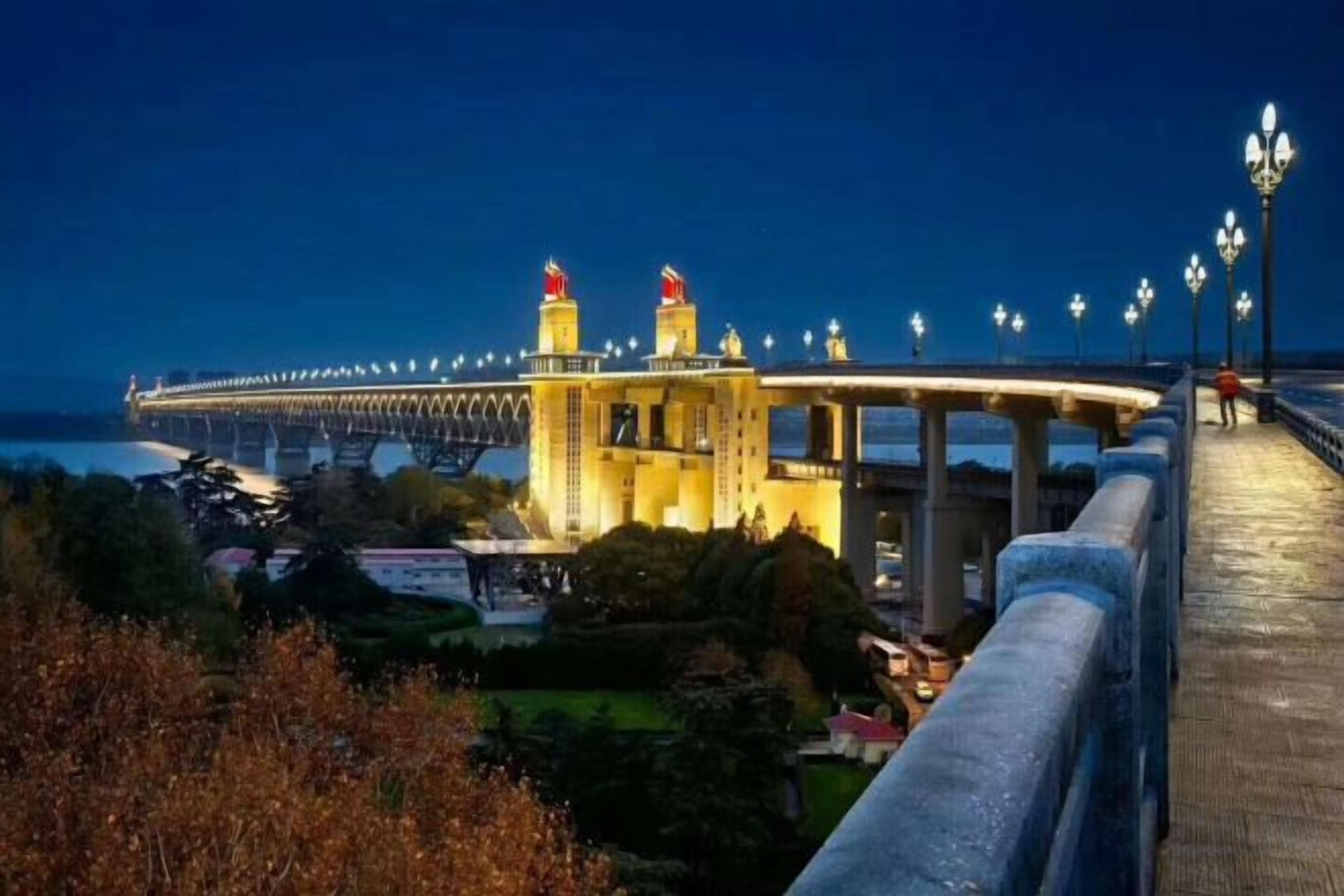 Une promenade en bord de mer avec un pont, un bâtiment arborant un drapeau et une rambarde.