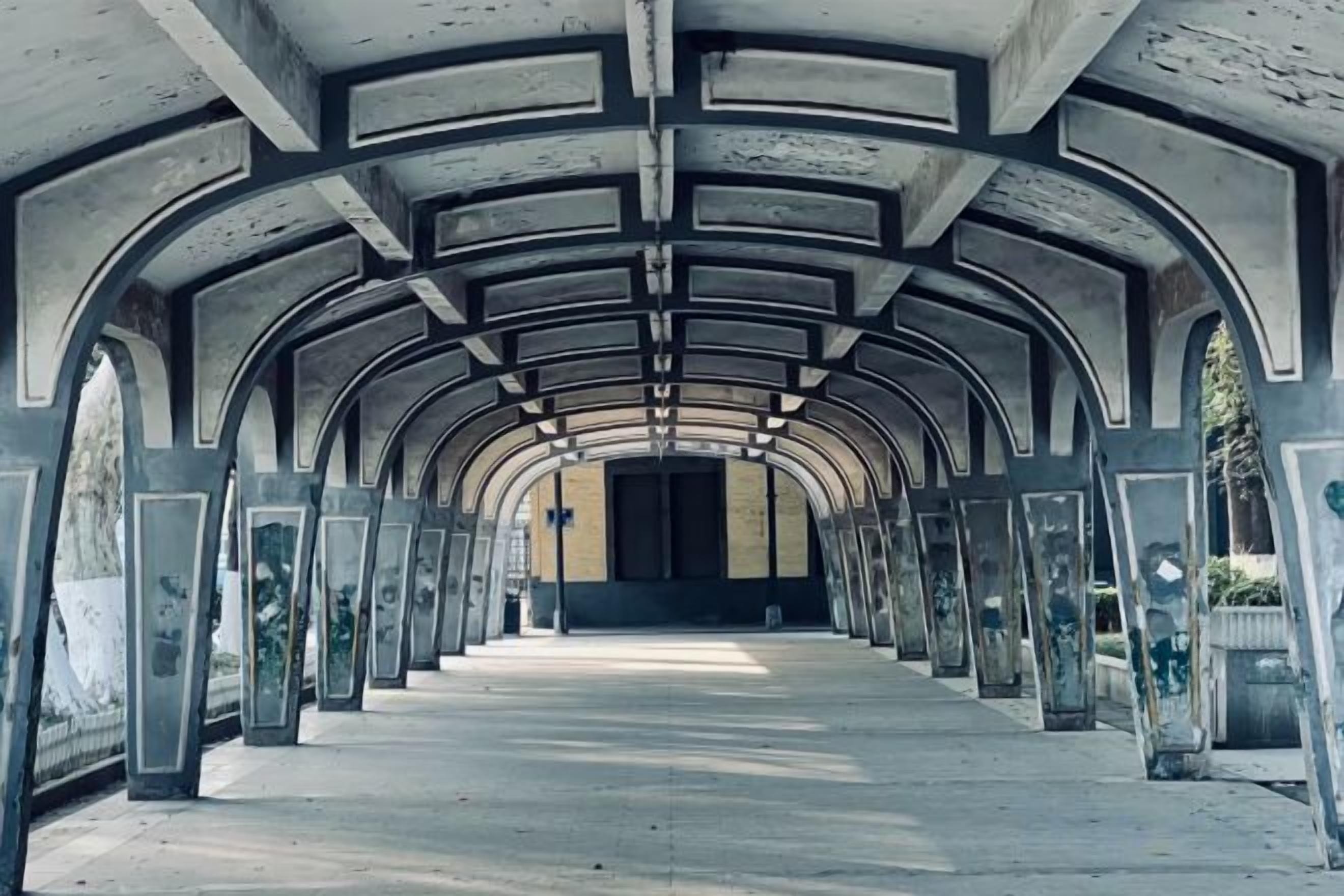 A corridor with a series of arches and columns, leading to a closed door at the end.