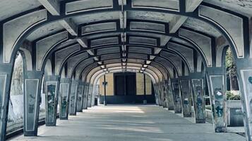 A corridor with a series of arches and columns, leading to a closed door at the end.
