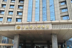 A hotel entrance with a modern facade, large windows, and a prominent sign. - Grand Daqiao Hotel (Nanjing)