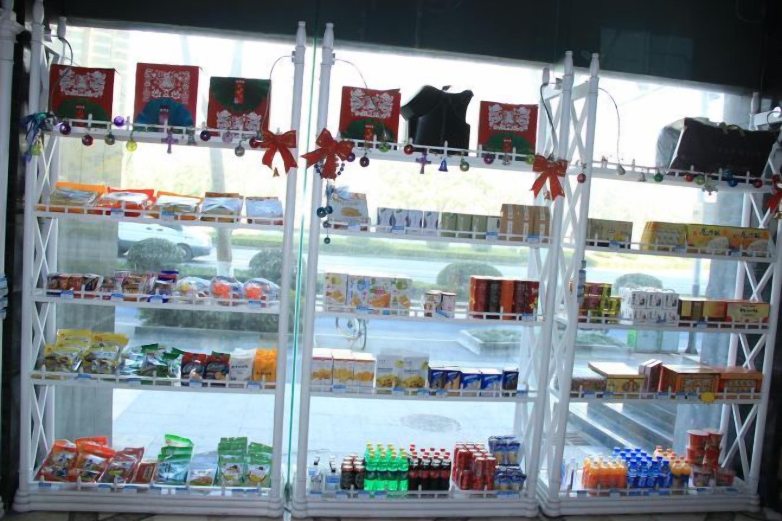 Un expositor de tienda con estantes llenos de diversos productos, entre ellos aperitivos y bebidas.