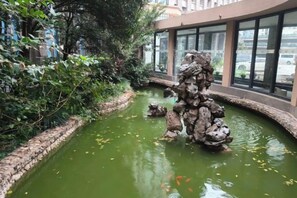 A water feature with rocks and a bridge, surrounded by greenery. - Grand Daqiao Hotel (Nanjing)