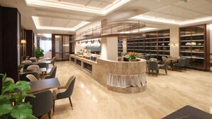 Un hall d’hôtel moderne avec un comptoir d’accueil incurvé, un espace salon et une grande bibliothèque.