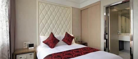 A hotel room with a large bed, a nightstand, a wardrobe, and a bathroom visible through an open door.