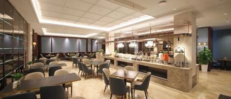 A modern restaurant with a central bar, multiple dining tables, and chairs.