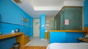 A hotel room with a bed, a desk, a chair, a trash bin, and a mirror. - Xiangshan Shipu Hongting Hotel (Xiangshan)