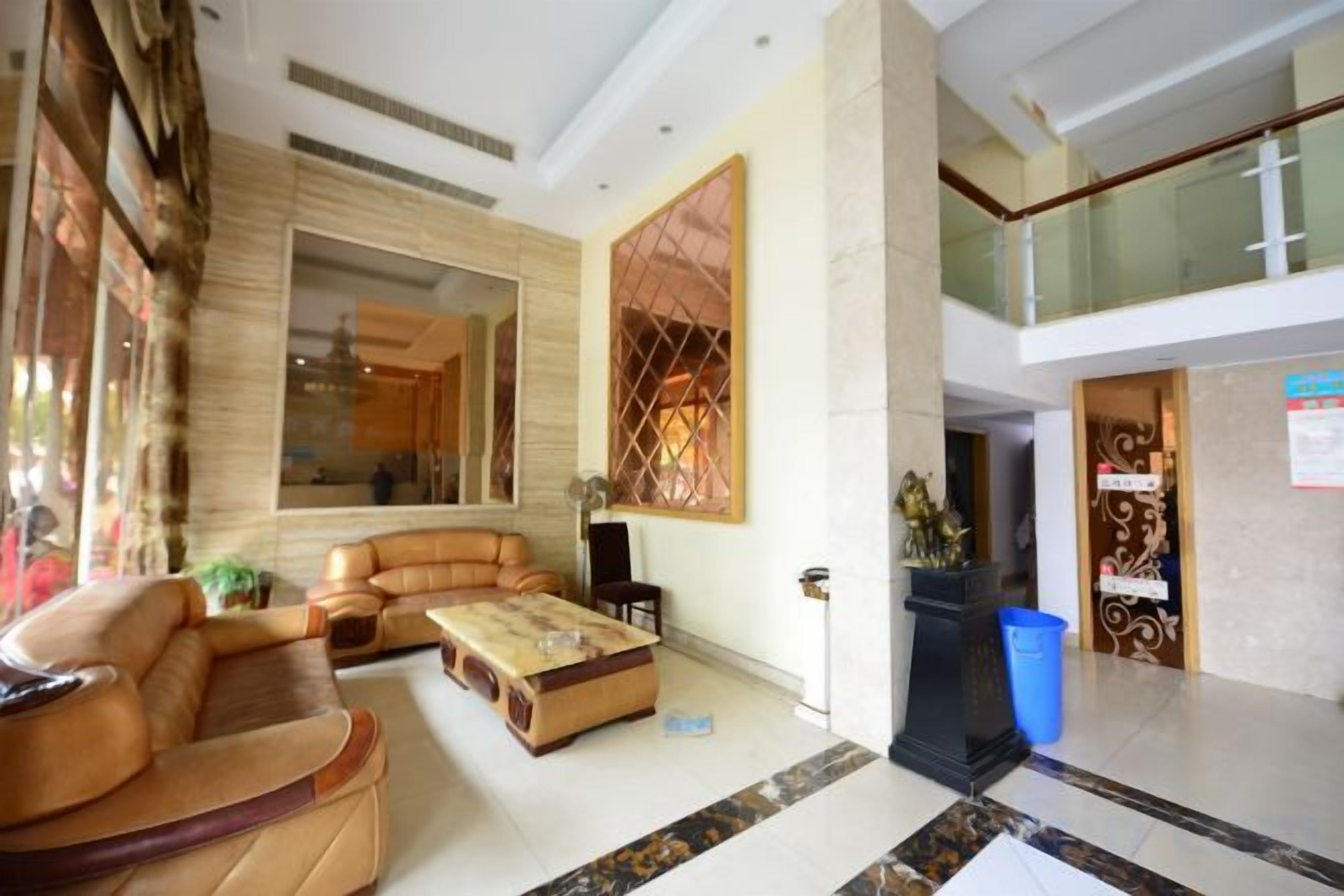 A spacious lobby with a leather sofa, a coffee table, and a large mirror.