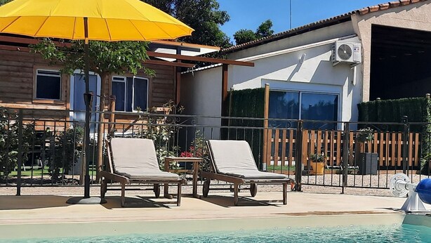 Une piscine avec des chaises longues et un parasol jaune.