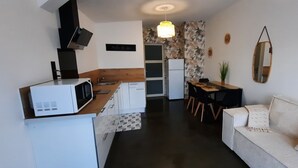 Un espace de vie compact comprenant un coin cuisine, un coin repas et un canapé.
