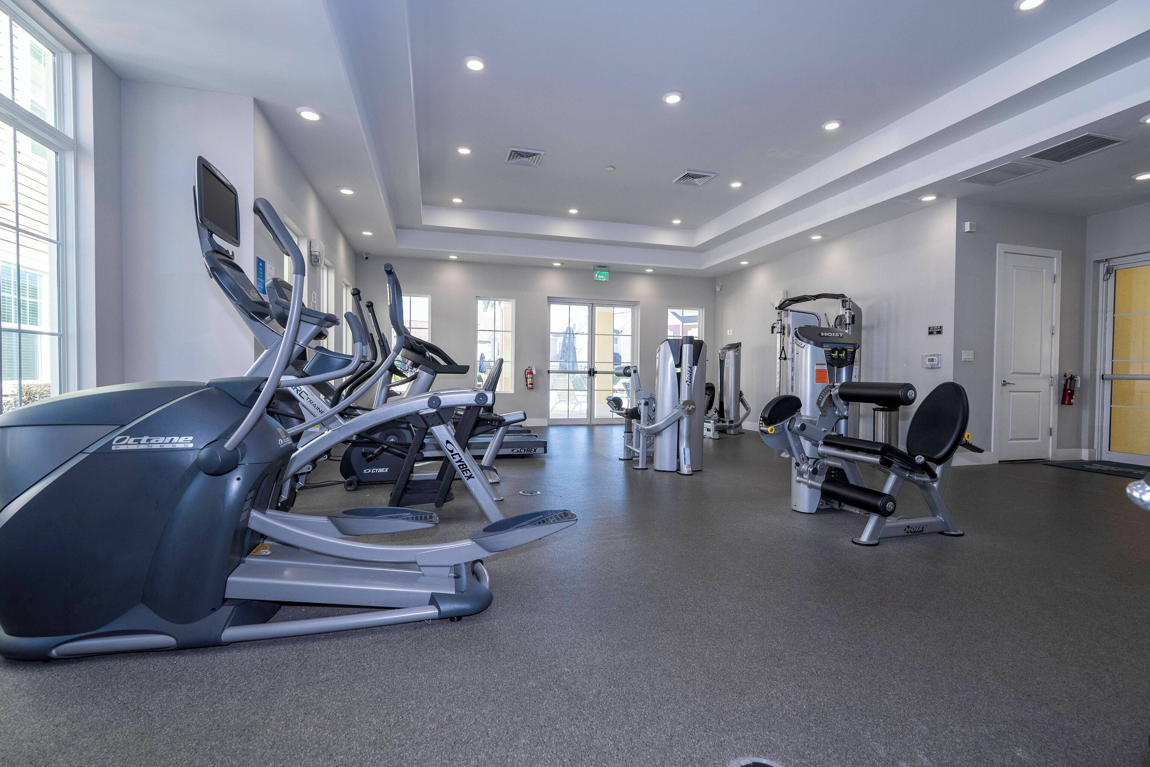 A gym with treadmills, weight machines, and a large window.