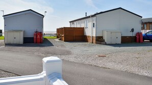 Un bâtiment avec un garage, une clôture en bois et une voiture bleue garée à proximité.