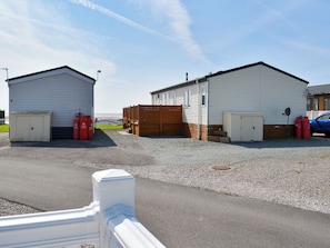 A building with a garage, a wooden fence, and a blue car parked nearby.