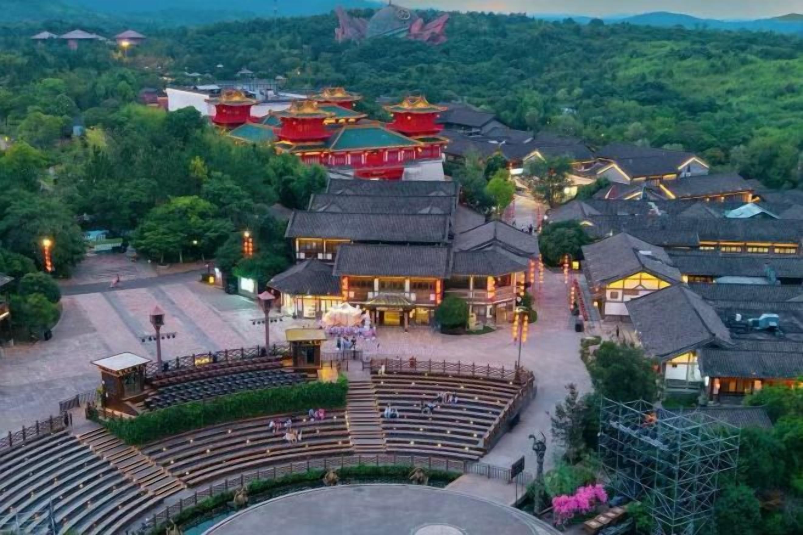 A traditional Chinese courtyard with a stage and audience seating, surrounded by buildings with red roofs.