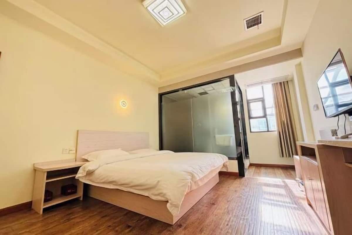 A bedroom with a bed, bedside table, and a TV.