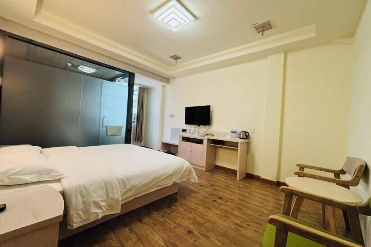 A hotel room with a bed, a desk, a chair, and a television.
