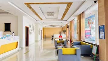 A hotel lobby with a reception desk, seating area, and large windows.