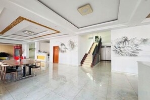 Uma sala de estar ampla com uma mesa de jantar, uma escada e obras de arte nas paredes.