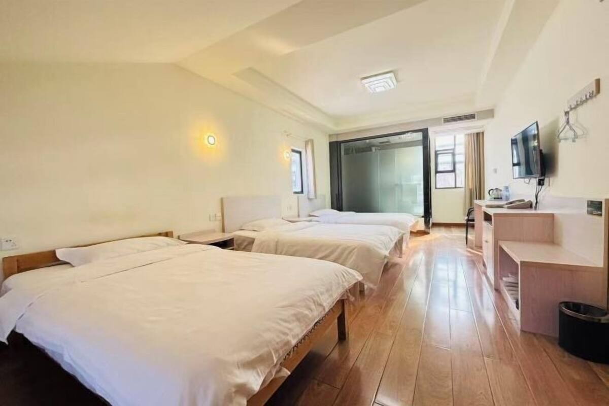 A hotel room with two beds, a desk, a television, and a sliding door leading to a balcony.