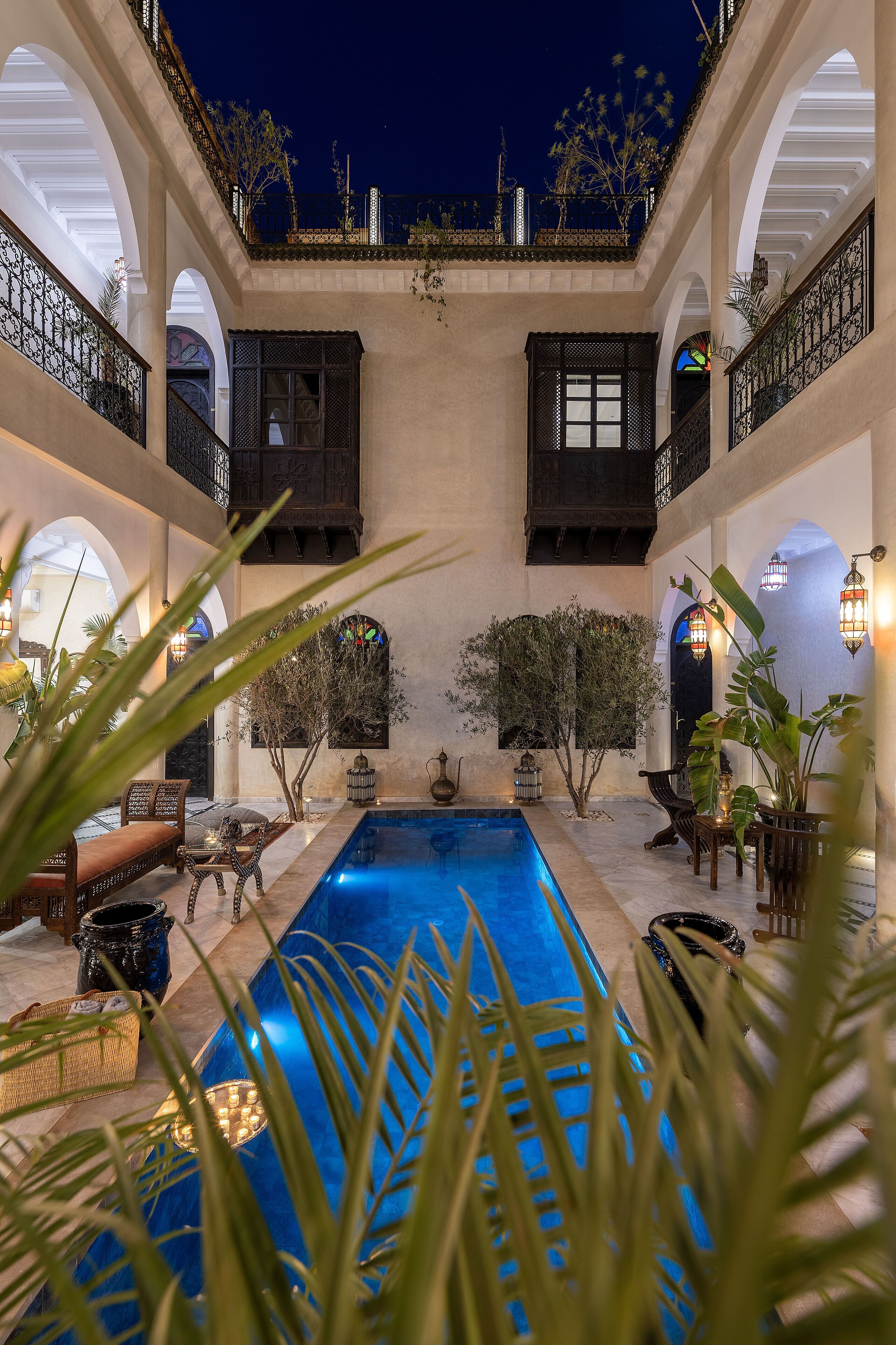 Un patio con piscina, zonas de estar y un balcón con plantas.
