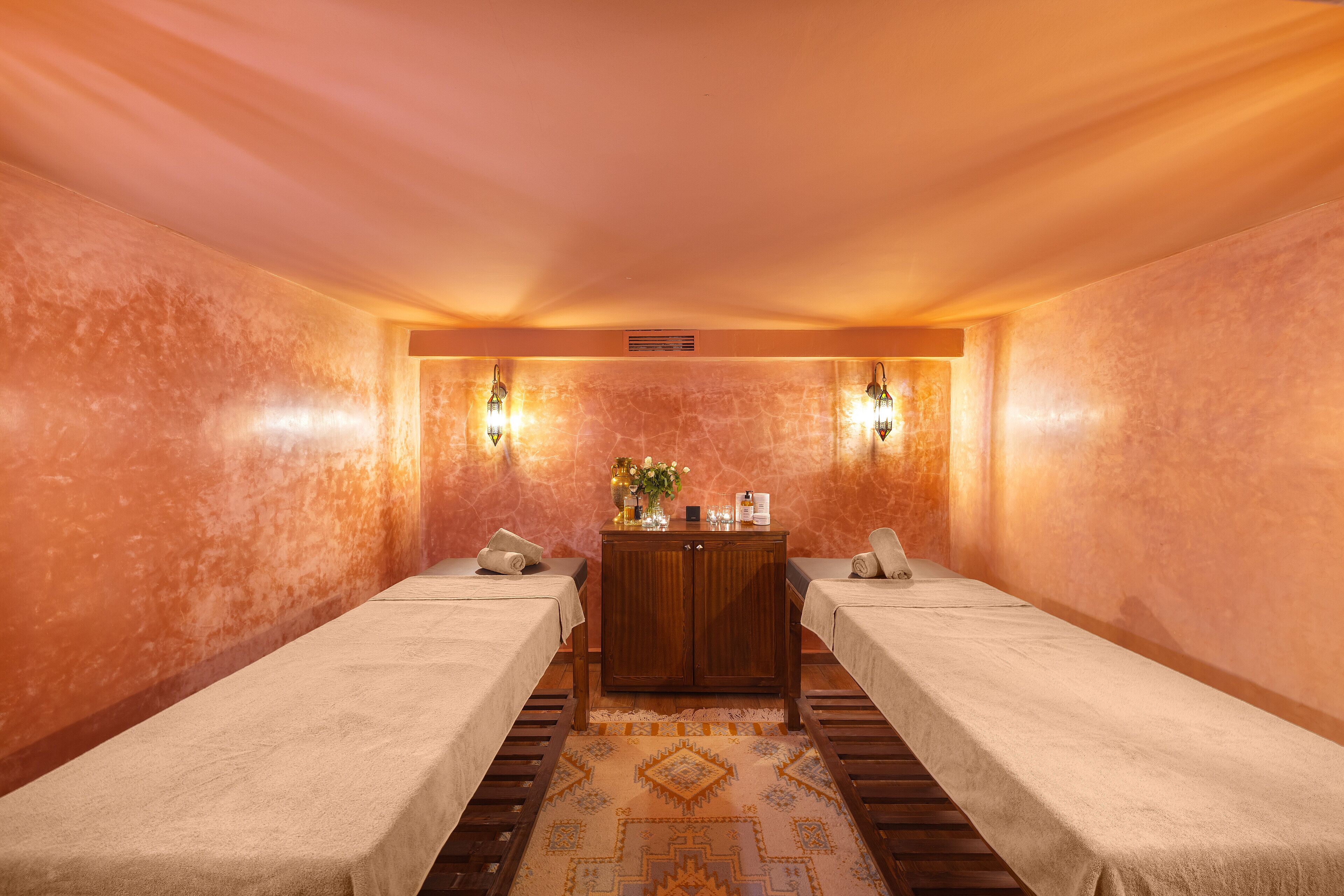 Un cuarto de spa con dos camas, un armario de madera y una alfombra estampada.