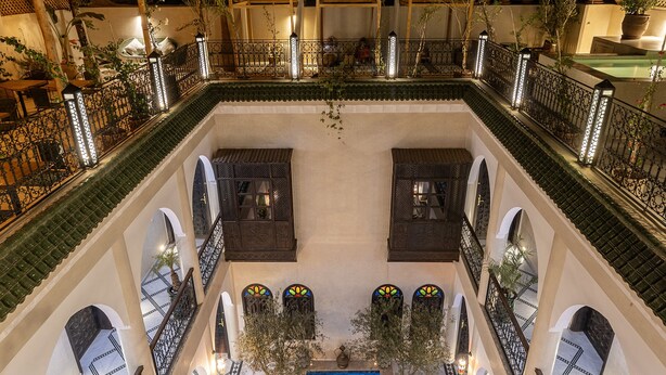 Un área de piscina de varios niveles, con una piscina central, múltiples balcones con barandillas y plantas en macetas.