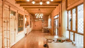 Un interior de madera con un largo pasillo, mesas y sillas de madera.