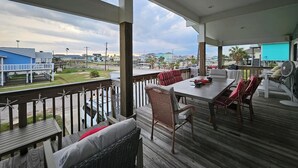 Un espacio al aire libre techado con mesa y sillas, una parrilla y vistas del entorno.