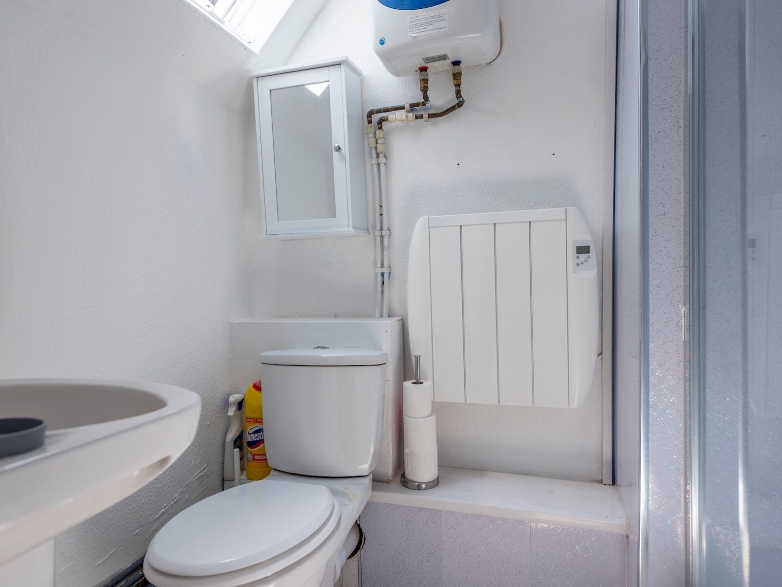 A compact bathroom with a toilet, a sink, and a white radiator.