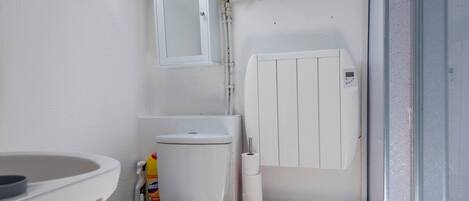 A compact bathroom with a toilet, a sink, and a white radiator.