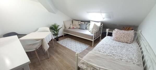 A compact room with a bed, a desk, a chair, a small table, and a potted plant. - Apartment Aveiro Center (Aveiro)