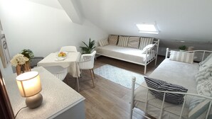 Un appartement moderne de style « loft », compact et aménagé avec un coin repas, un canapé et un lit.