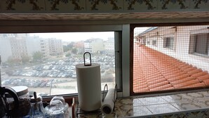 Une cuisine avec une fenêtre donnant sur un parking et des immeubles.