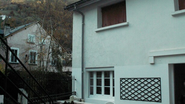 A white building with a balcony, a lattice window, and a mountain in the background. - A 10 Minutes des Thermes et des Remontées, Appartement Classé 2 Étoiles (Cauterets)
