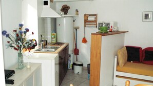 A compact kitchen with a sink, stove, and a small dining area with a table and chairs. - A 10 Minutes des Thermes et des Remontées, Appartement Classé 2 Étoiles (Cauterets)