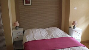 A neatly made bed with a pink blanket, two bedside tables with lamps, and a wall-mounted picture. - A 10 Minutes des Thermes et des Remontées, Appartement Classé 2 Étoiles (Cauterets)